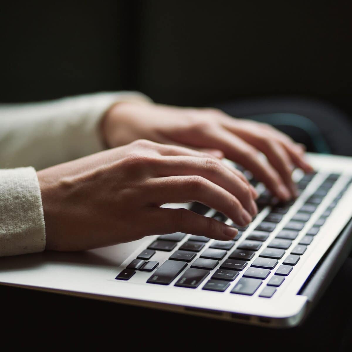 Hands typing on a laptop at a design workspace
